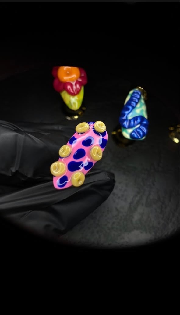 Colorful nail art pieces displayed on a black surface