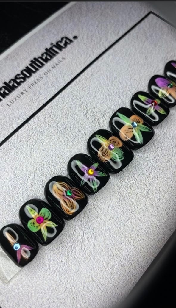 Black press-on nail set with hand-painted floral designs and gemstone accents
