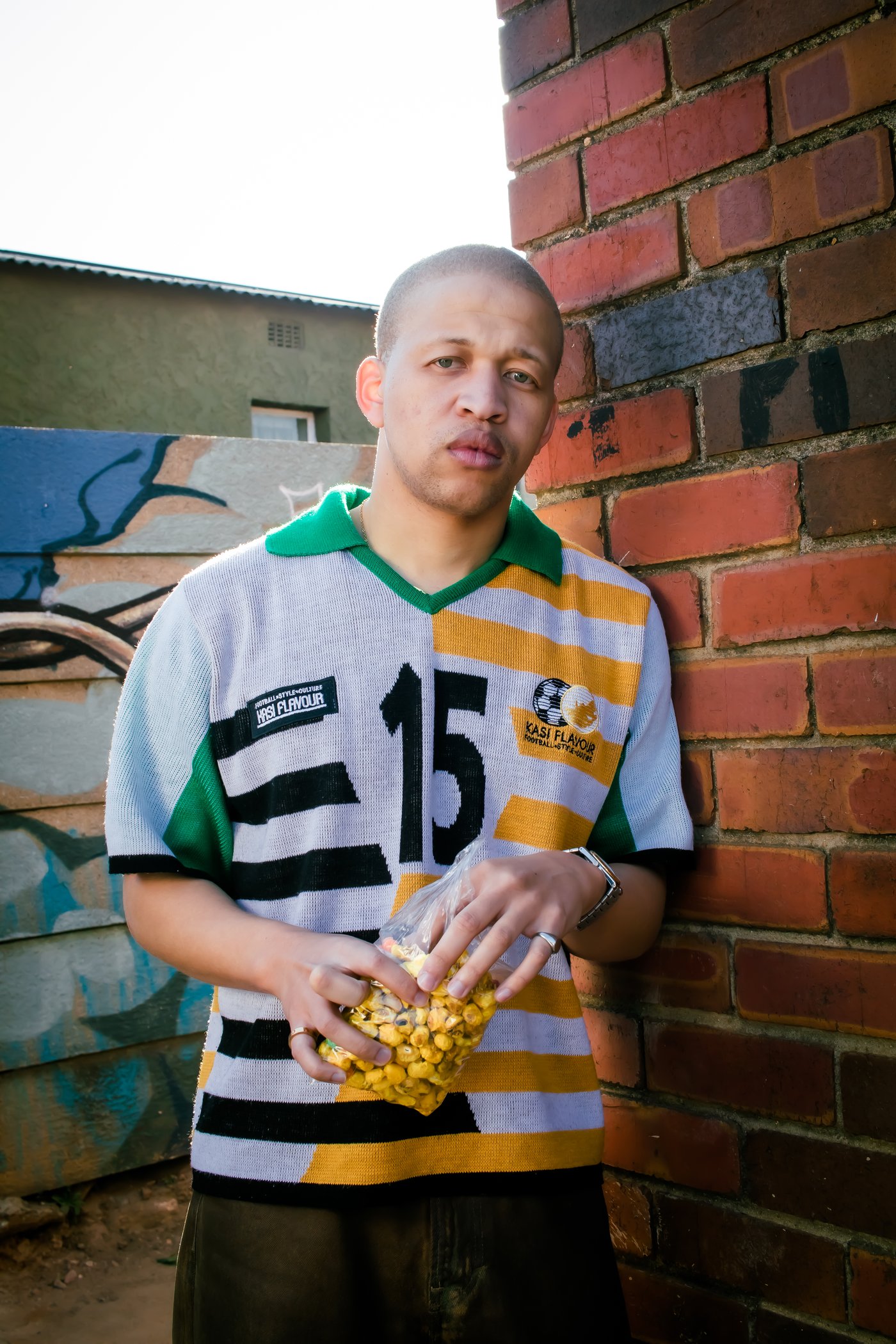 From Daily Click: man in white and yellow number 15 Kasi Flavour jersey holding a bag of ama kip kip chips